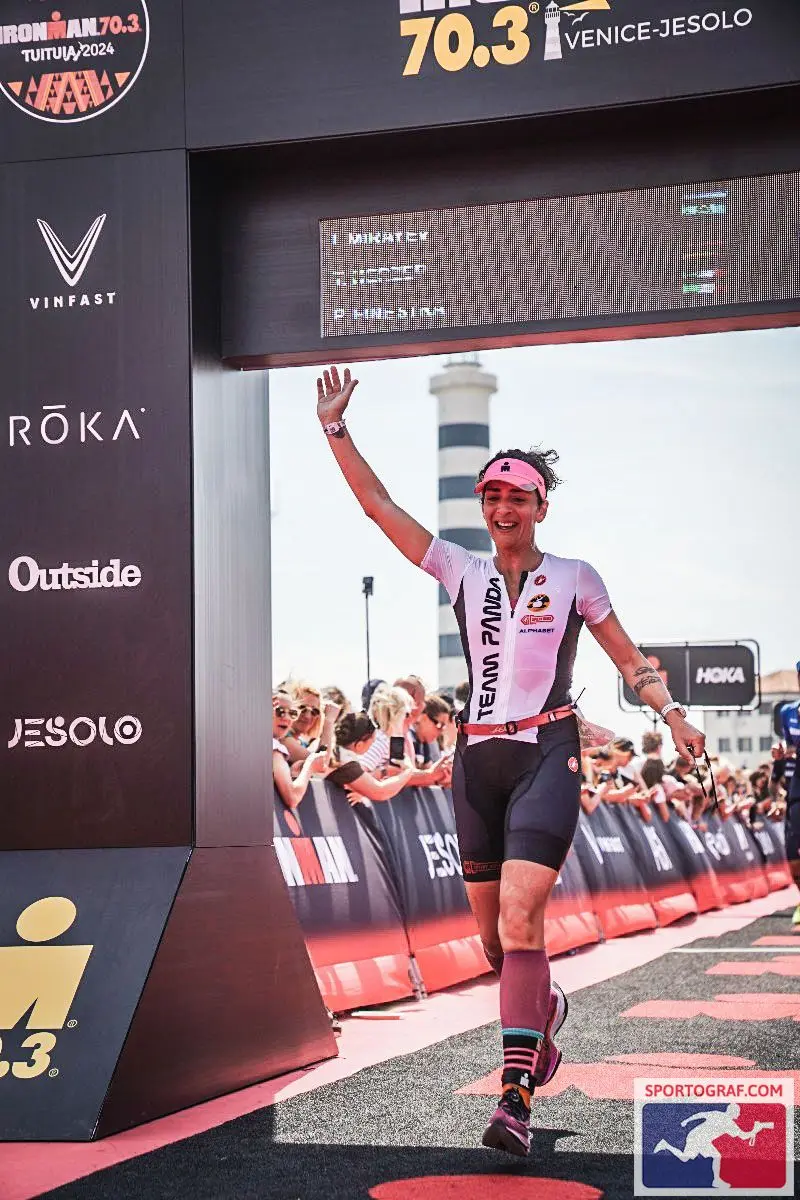 Atleta Team Panda celebra sotto l'arco di arrivo di una gara serale